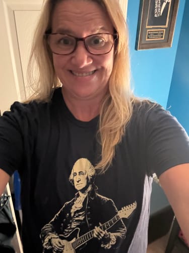 Customer's Washington 250 T-Shirt with George Washington playing an electric guitar, worn by a smiling reviewer.