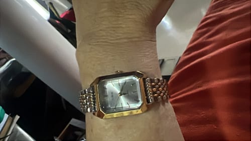 Customer's gold-toned Claire De Mains watch on their wrist with a classic metallic link band.