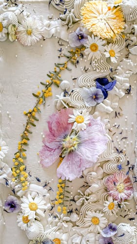 Reviewer's cake decorated with Light Purple Violas, small yellow flowers, and white piped frosting detail.