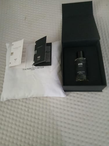 Customer's Lilium Blume perfume bottle, product box, and white bag with promotional literature on a textured surface.