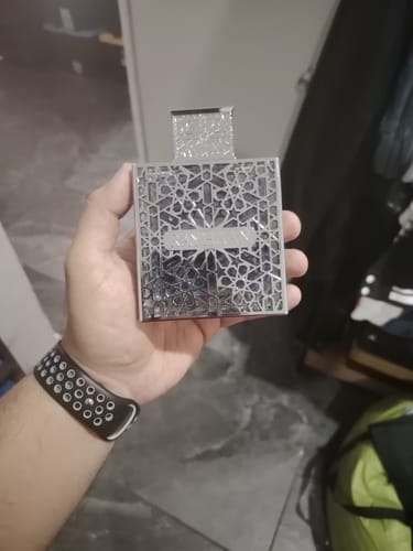 Customer's hand holding the silver, intricate Rayhaan Aquatica perfume bottle.
