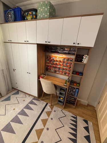 Customer's Rani BA122 wardrobe and desk setup in a room, featuring white cabinets and wooden shelves with toys.