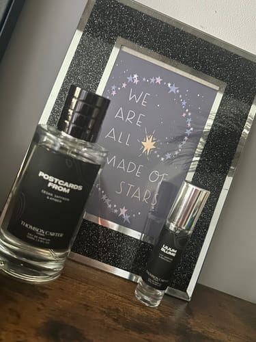 Customer's Lilium Blume perfume bottle standing on a wooden surface in front of a framed inspirational print.