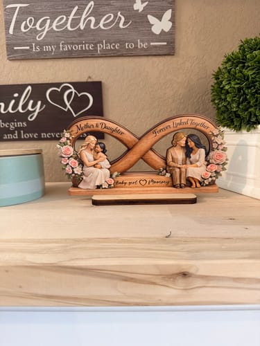 Customer's wooden Mother & Daughter plaque displayed on a wooden shelf with decorative floral accents.