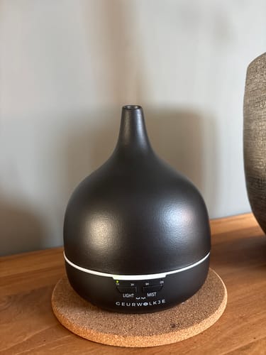 Customer's Midnight Black Geurwolkje diffuser on a round cork coaster, showing the sleek design.