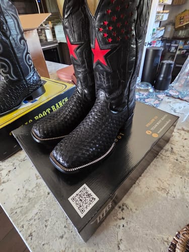 Customer's Black Basketweave Leather Boots with red star detailing, resting on a branded boot box.