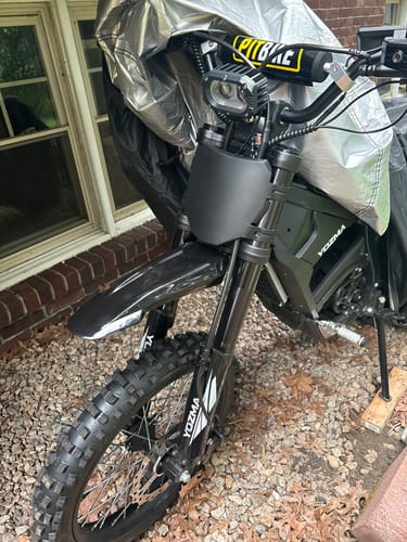 Customer's black Surron front fender installed on an electric dirt bike, shown from the front.