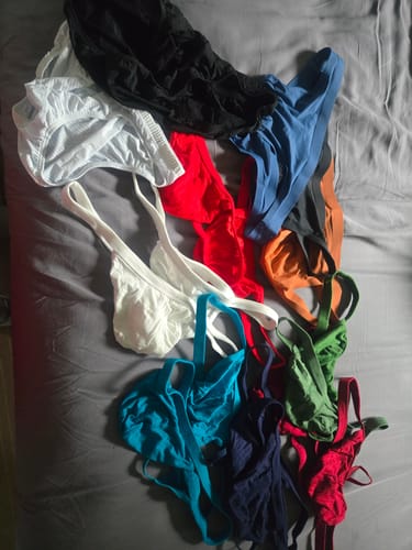 Customer's collection of Modal thongs in multiple vibrant colors spread out on a grey surface.