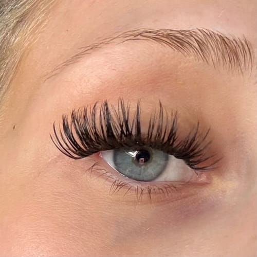 Customer's Auge mit aufgetragenen Heart To Break Wimpernextensions, die einen dramatischen Wimpernaufschlag zeigen.