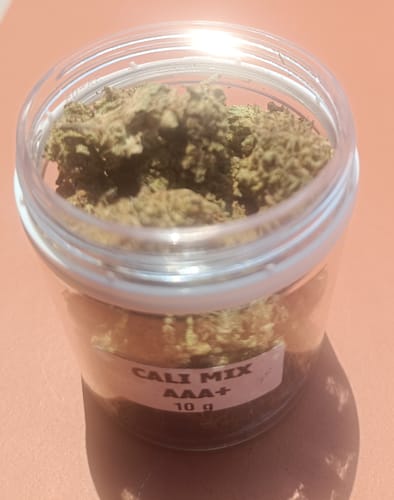 Reviewer's Cali Mix AAA+ premium flowers in a clear plastic jar with a label.