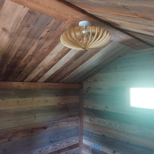 Customer's Mini Néo plafonnier en chêne installé au plafond d'un mazot en bois.