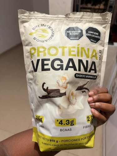 Reviewer's hand holding a bag of Proteína Vegana, flavor vainilla, clearly showing the product labeling.