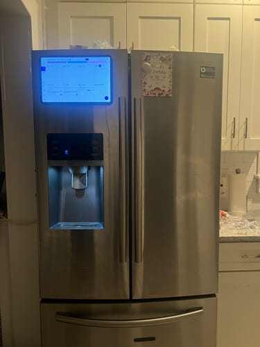 Customer's Everblog FridgeCal mounted on a stainless steel refrigerator door, displaying a glowing digital calendar.