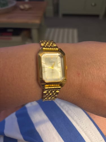 Customer's gold-toned Claire De Mains watch with a classic rectangular face worn on their wrist.