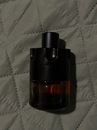 Customer's Azzaro The Most Wanted fragrance bottle, standing on a textured surface.