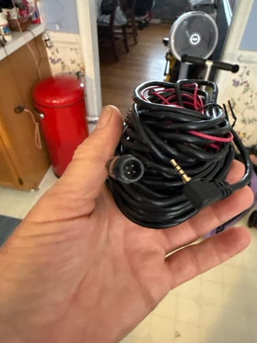 Customer's hand holding a coiled black WOLFBOX rear camera replacement cable with a connector and a jack plug.