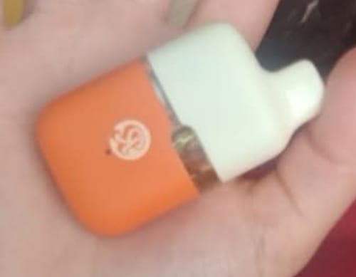 Customer's hand holding a compact, orange and cream-colored ROLLZ THCA vape device.
