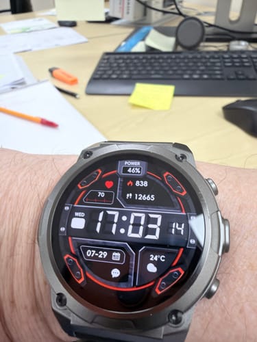 Reviewer's wrist wearing the Gard Pro Ultra 3 watch showing a digital screen with 46 percent battery, on a desk.