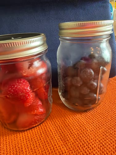 Customer's Mason Genie Vacuum Sealer Kit used on two clear mason jars containing fresh strawberries and blueberries.