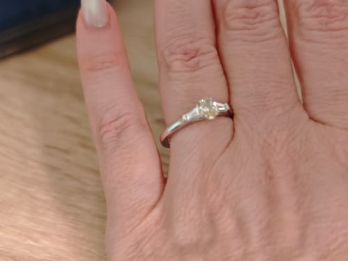 Customer's custom oval yellow stone ring with baguette accents on their finger