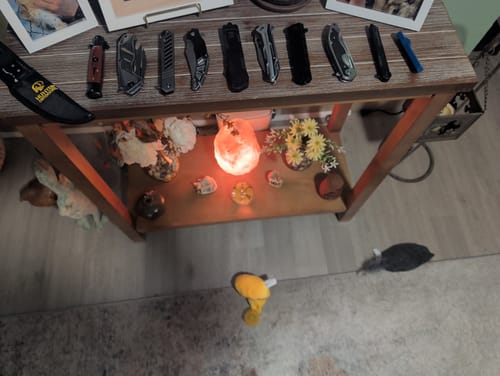 Customer's collection of Mystery Knife Pack blades, including folding and fixed knives, displayed on a wooden table.