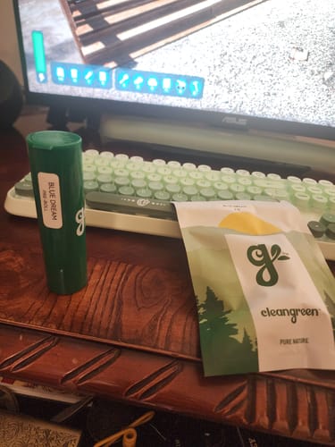 Reviewer's order with a green pre-roll tube and product pouch on a wooden desk.