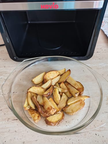 Client arătând un bol cu cartofi aurii proaspăt gătiți cu friteuza Air Fryer Novio StonePro.