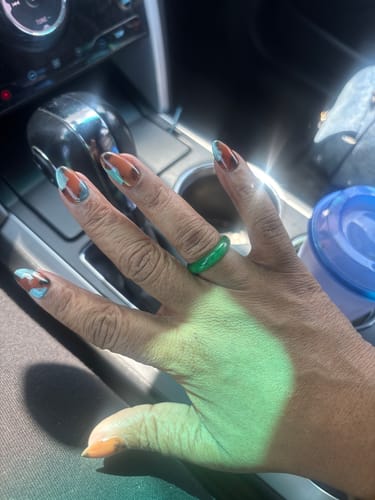 A customer's hand wearing the solid green Jade Ring while in a car.