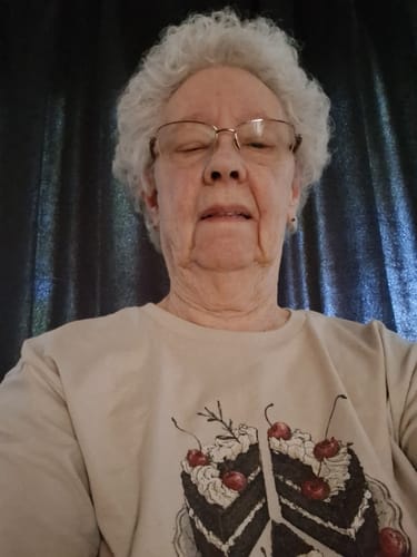 Reviewer wearing the beige Peace Of Cake t-shirt with a graphic of two cake slices forming a peace sign.