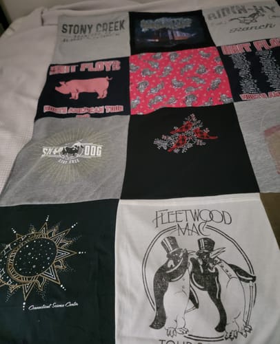 Customer's custom Project Repat T-shirt Quilt, showing a colorful patchwork of various graphic tees laid on a bed.