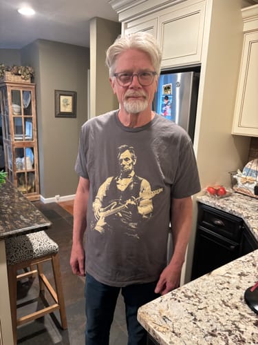 Reviewer standing in a kitchen wearing the grey graphic Lincoln Guitar T-Shirt.