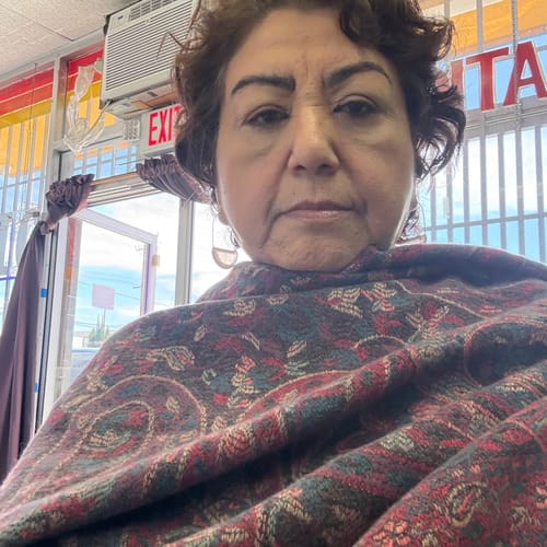Close-up of a customer wearing the patterned ethnic flower tassel shawl wrapped around her shoulders.