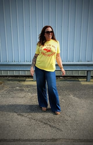 Customer wearing the yellow Just a Girl Who Loves Peckers Tee with wide-leg jeans outdoors.