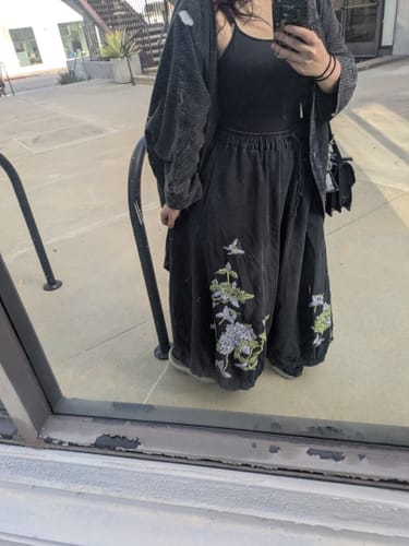 Customer's retro wide-leg jeans with floral embroidery, shown worn while standing outdoors.