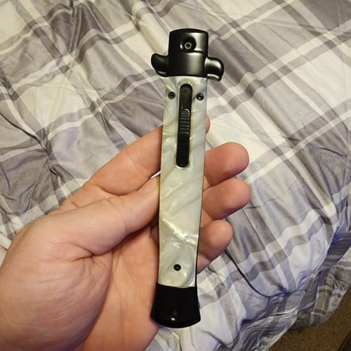 Customer's hand holding a sleek, white marbled-pattern knife with a black handle and clip.
