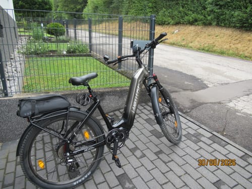 Customer's Lankeleisi MG600 Lite electric bike parked on a paved driveway next to a metal fence.