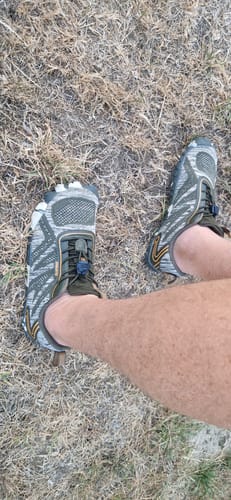 Customer's Active II Pro barefoot shoes on feet while walking on dry grass.