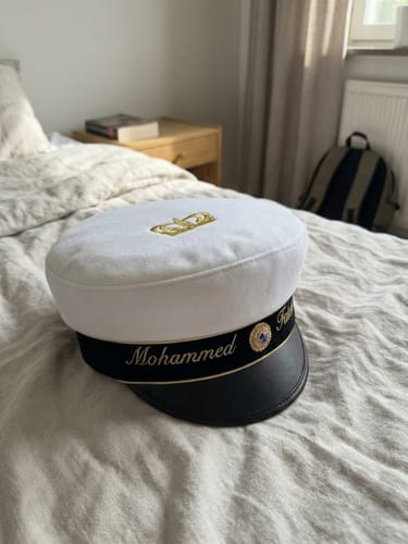 Mössan med namnet Mohammed i guld, liggande på en säng