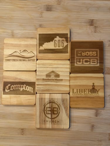 Customer's AtomStack Atelier laser-engraved wooden coasters with various church and custom logos.