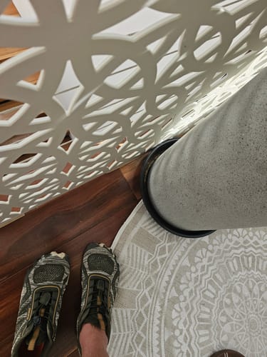Customer's Active II Pro barefoot shoes on feet, featuring camouflage knit pattern, worn on wood floor near a round mat.