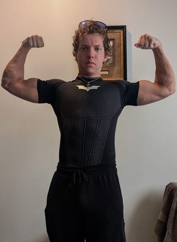 Customer's Batman Compression Tee, showing the fitted, black shirt with a Batman emblem while flexing in a gym pose.