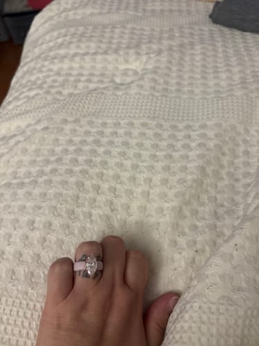 Customer's hand wearing a Marquise Cut Silicone Ring with a clear stone on a white textured blanket.