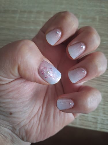 Reviewer's Hand mit Babyboomer Nude UV Gel Nail Wraps und kleinen Schmucksteinen im Farbverlauf von Nude zu Weiß