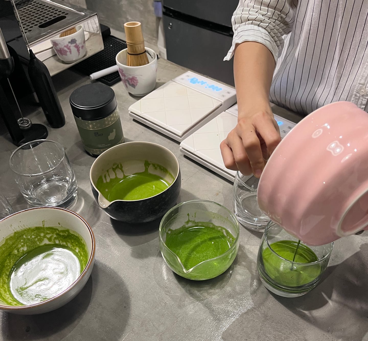 Customer preparing vibrant green matcha from a pink bowl.