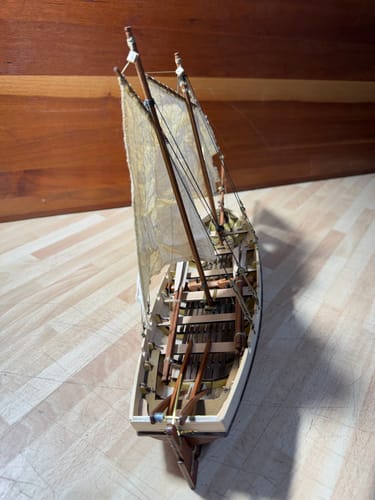 Customer's Bounty Boat wooden model seen from above, showing sails, rigging, and internal deck seating.