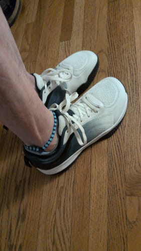 Customer's CUURT Muuv court shoes on feet, showing the white and dark gray gradient design on a wood floor.