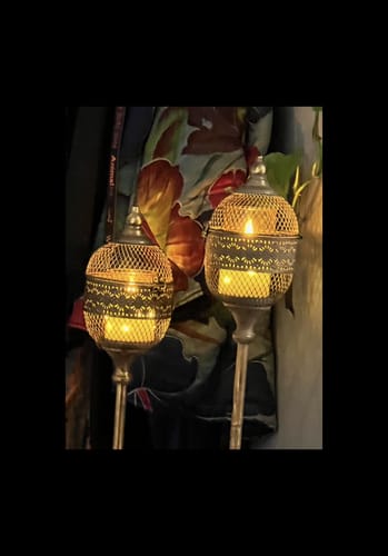 Customer's pair of Astrid French Provincial candle lanterns glowing with warm light in a cozy, dim setting