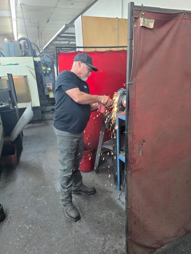 Reviewer in a workshop using a grinding tool, sparks flying while working, helping them get back to work.
