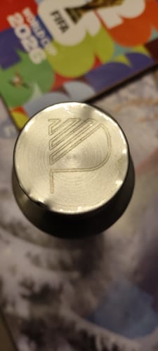 Customer's metal item with a circular engraved logo at the center, close-up.