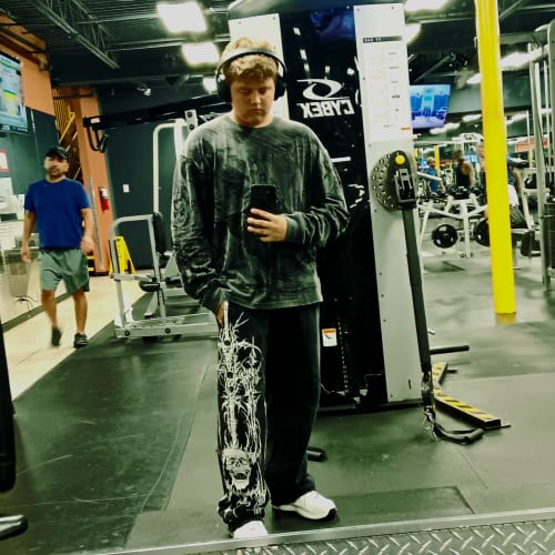 Customer's Eternal Embroidered Sweats, worn in a baggy fit at the gym, showing detailed gothic-style leg embroidery.